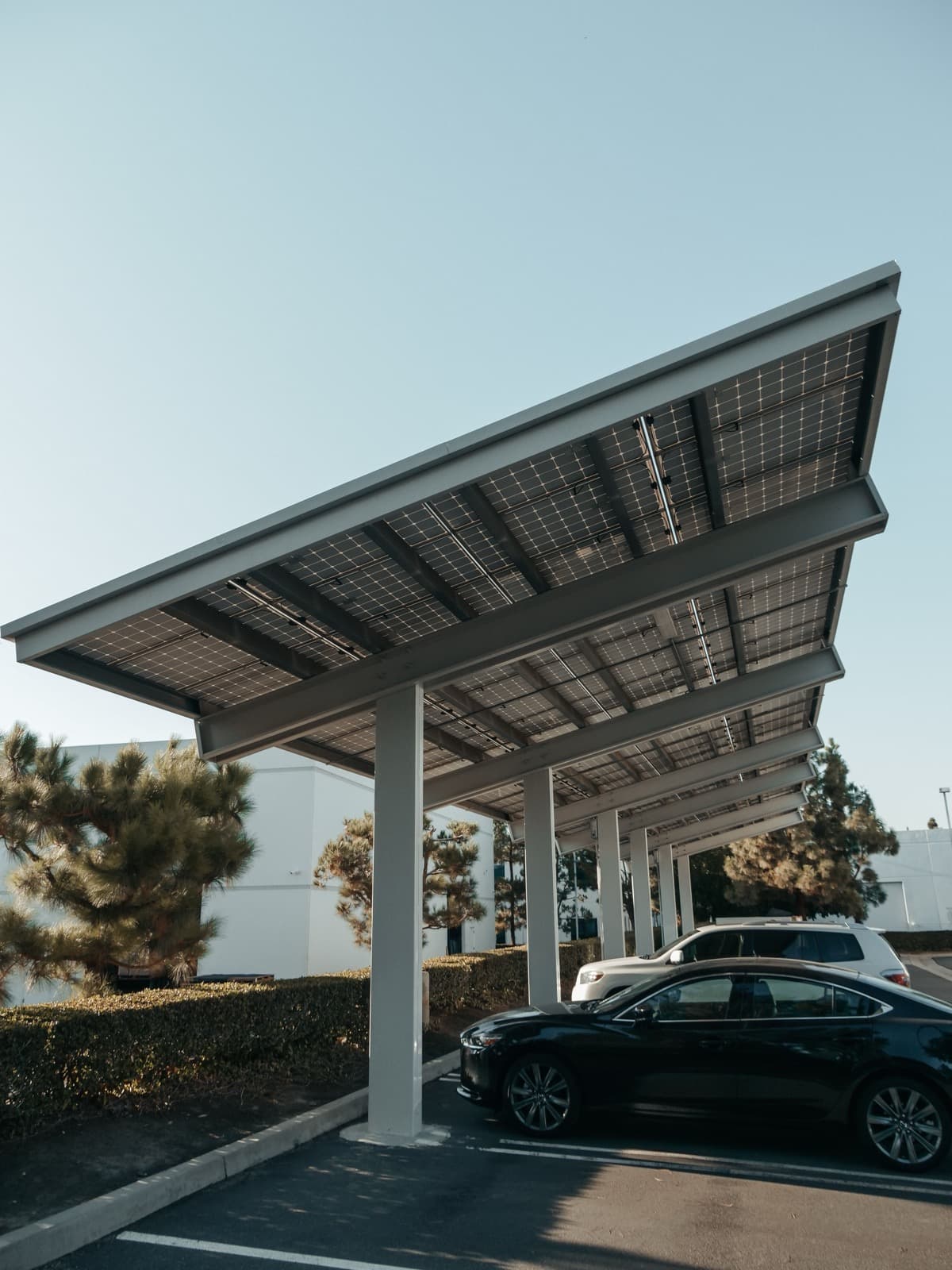 A steel-framed solar carport canopy over parked cars